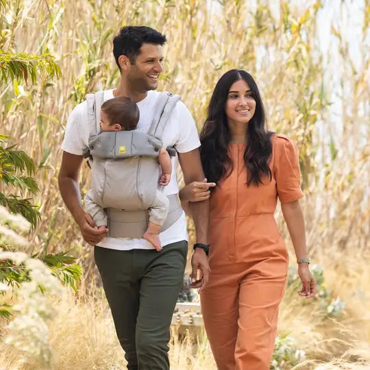 Mother and Father hike in the corn field holding their baby in a LILLEbaby carrier