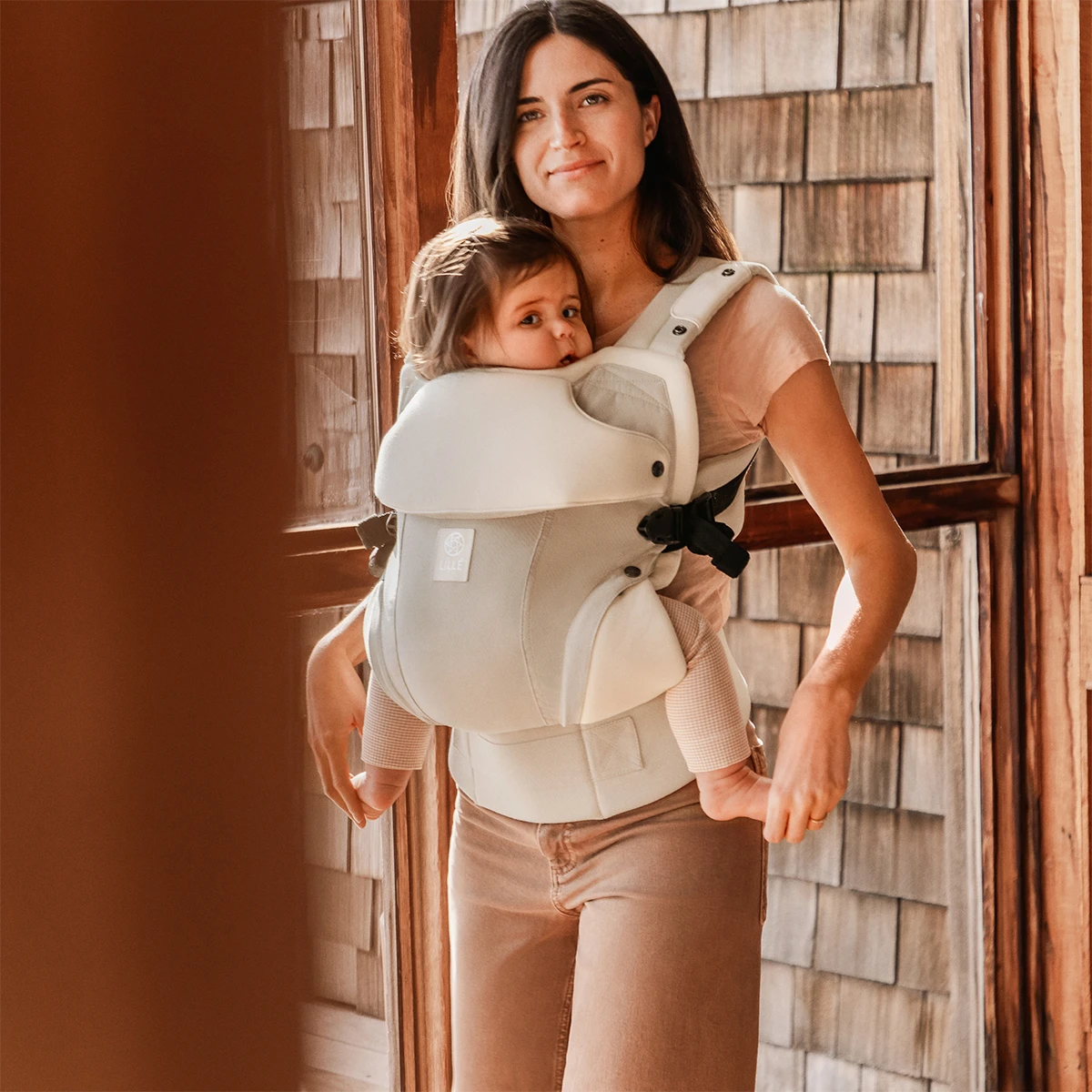 mom wearing baby in elevate carrier in ivory