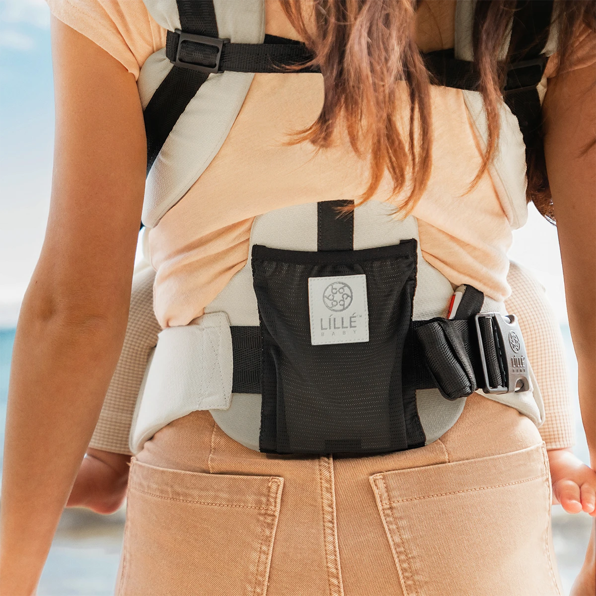 close up image of mom wearing baby in Elevate 6-in-1 Baby Carrier in Ivory showing mainly the lumbar support