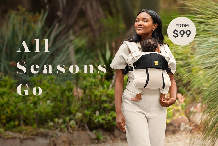 All Seasons Go - carrier from $99. Image showing mom wearing infant child in ivory colored baby carrier walking on a trail.