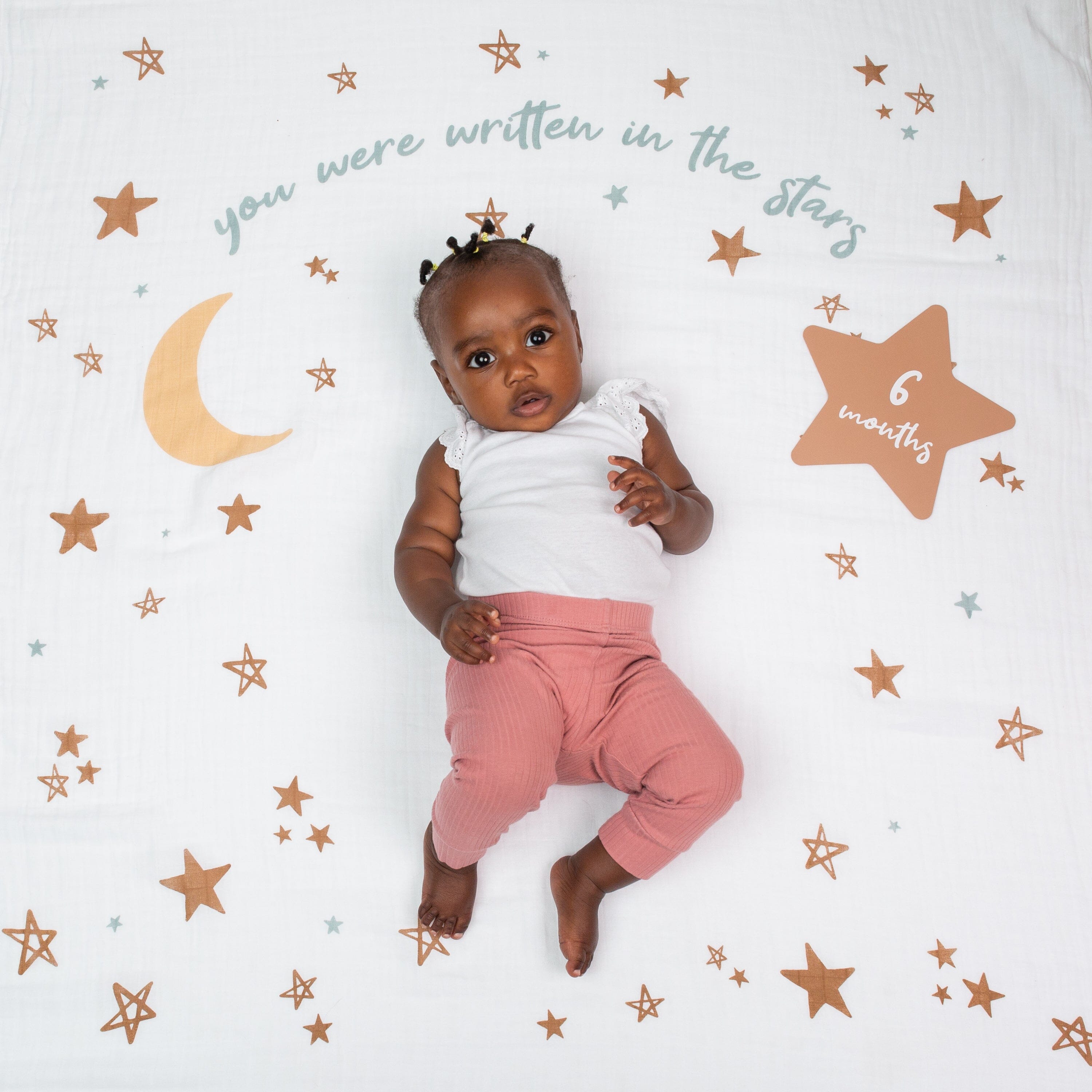 6 months old baby on lulujo blanket in written in the stars pattern