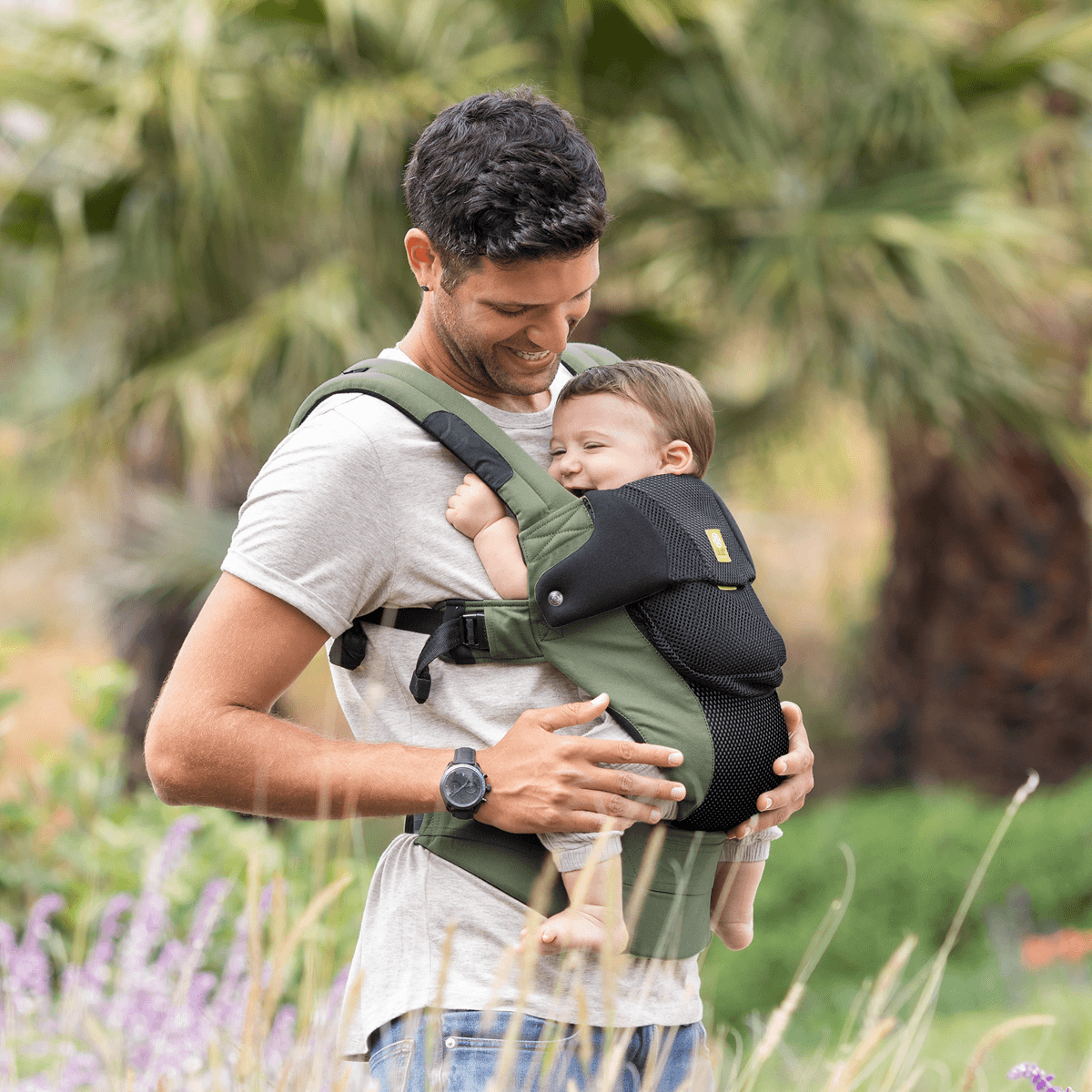 Dad holding baby in a green LILLEbaby Complete carrier
