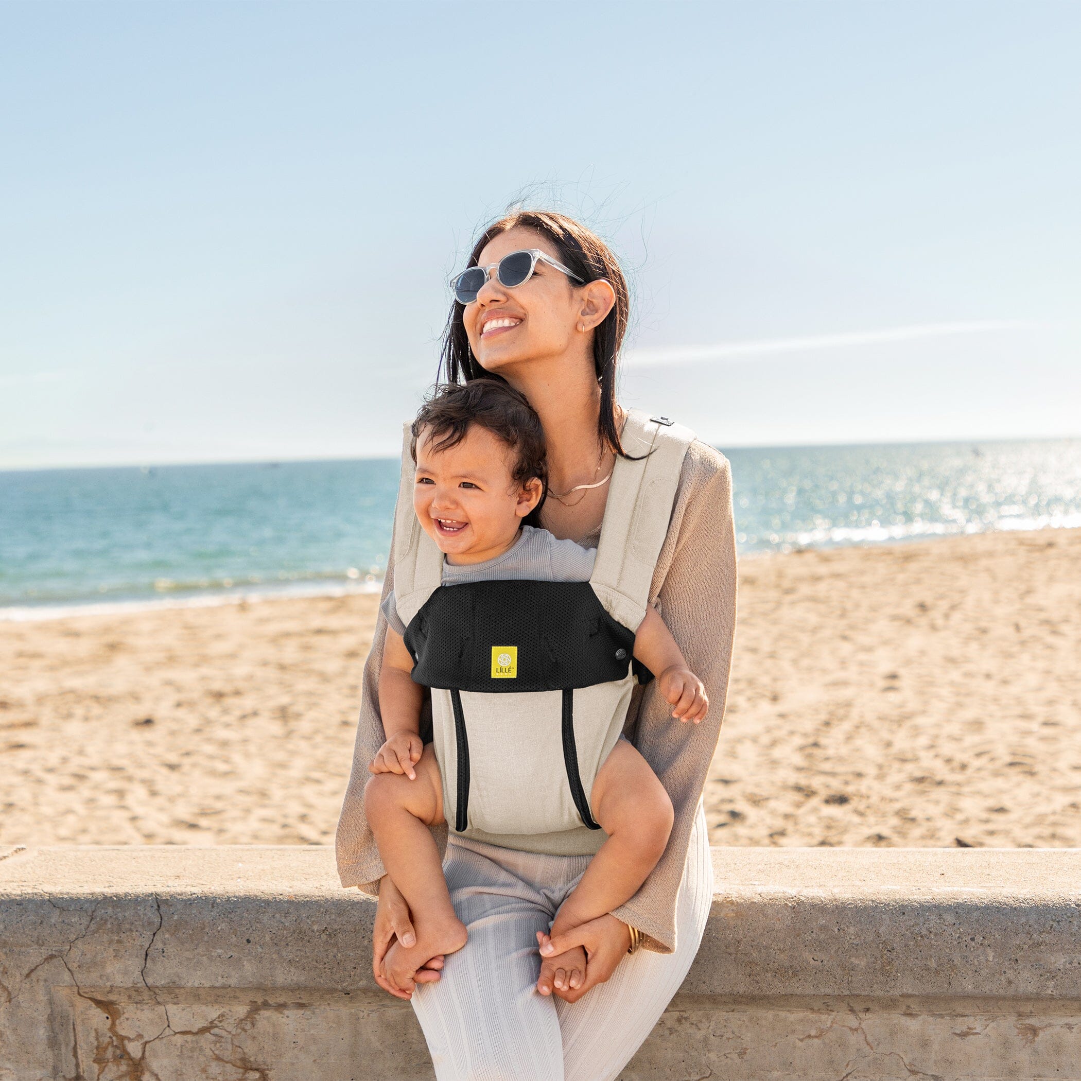 Mom wearing baby in Lillebaby Complete 6-in-1 All Seasons Carrier in Moonbeam by the beachside