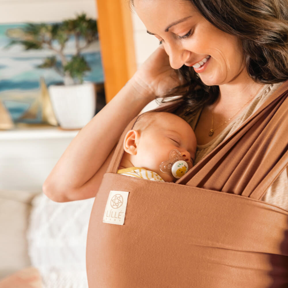 mom wearing baby in lillebaby's dragonfly wrap in butterscotch