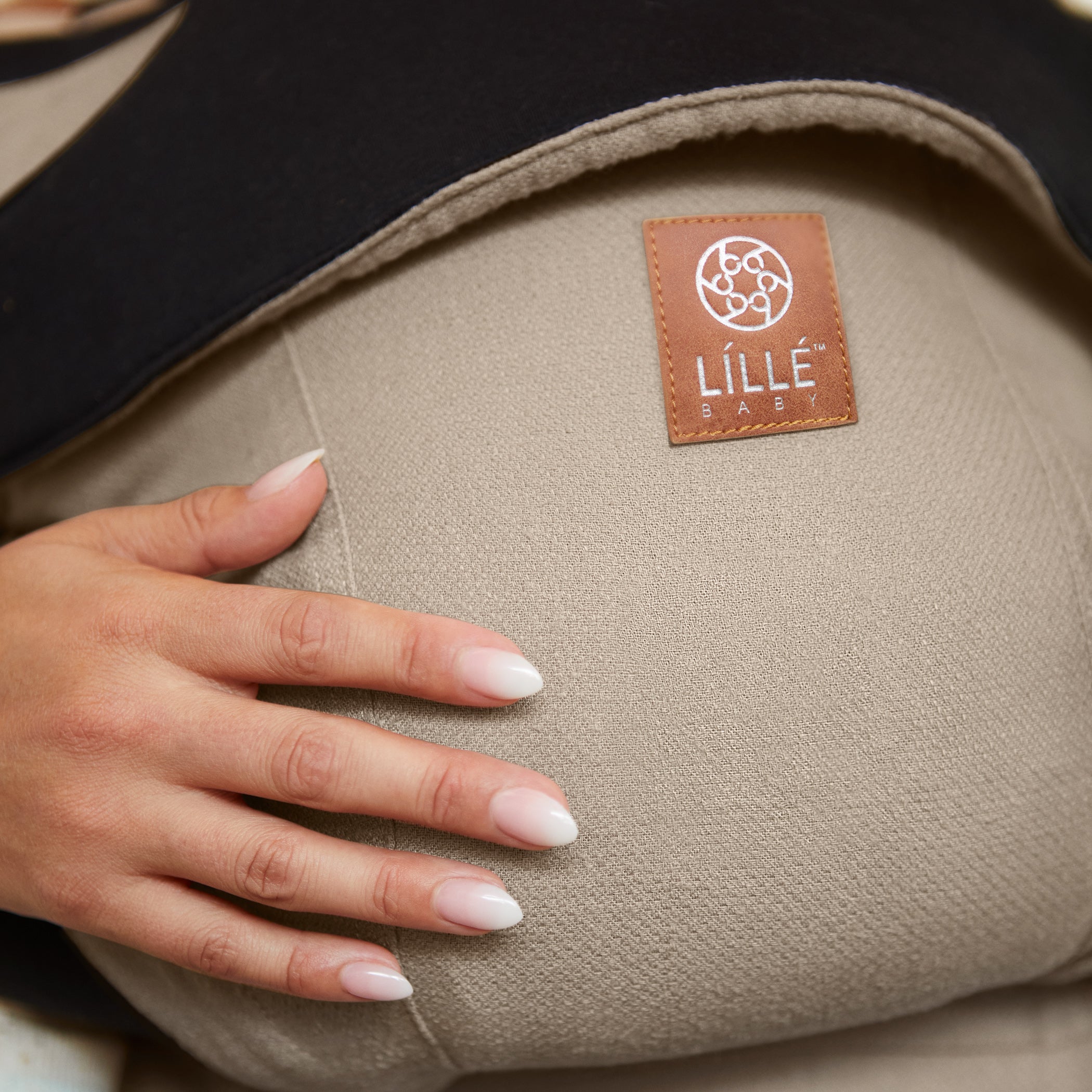 mom wearing baby in elevate carrier in warm sand