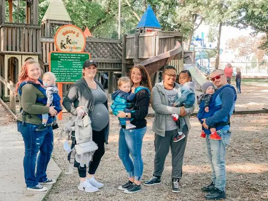 Moms and Dads holding their babies in LILLEbaby carriers on the playground