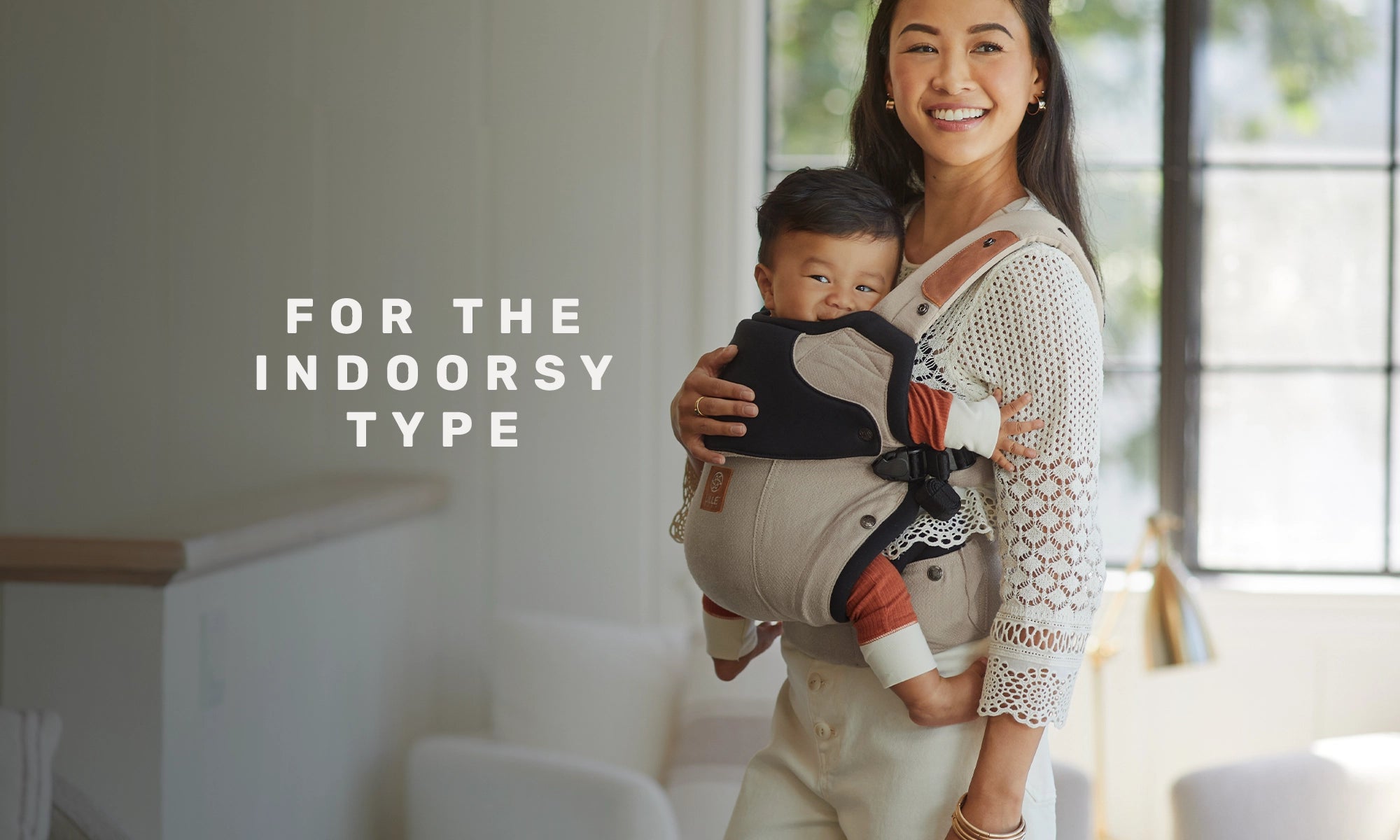 for the indoorsy type. mom wearing baby in the elevate carrier in warm sand