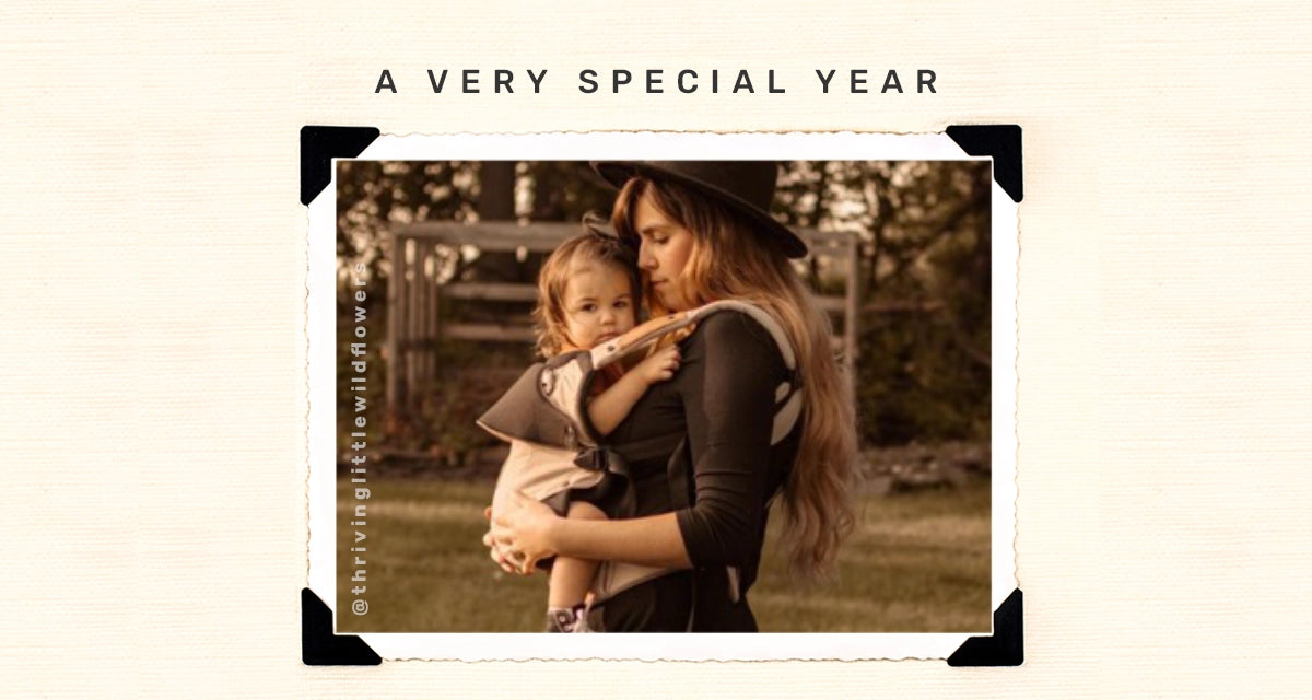 a very special year. mom wearing toddler in elevate carrier. image from @thrivinglittlewildflowers