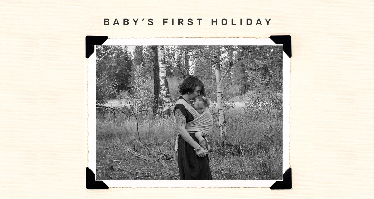 baby's first holiday. mom wearing baby in dragonfly wrap in the woods