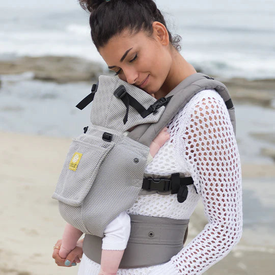 Mom holding baby in carrier on the beach