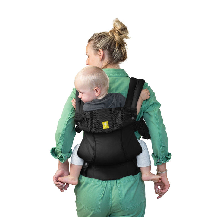 back image of mom wearing baby in lillebaby complete all seasons baby carrier in black