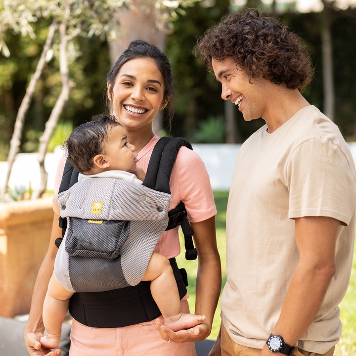 mom wearing baby in lillebaby complete airflow baby carrier in charcoal silver while dad and baby smile at each other