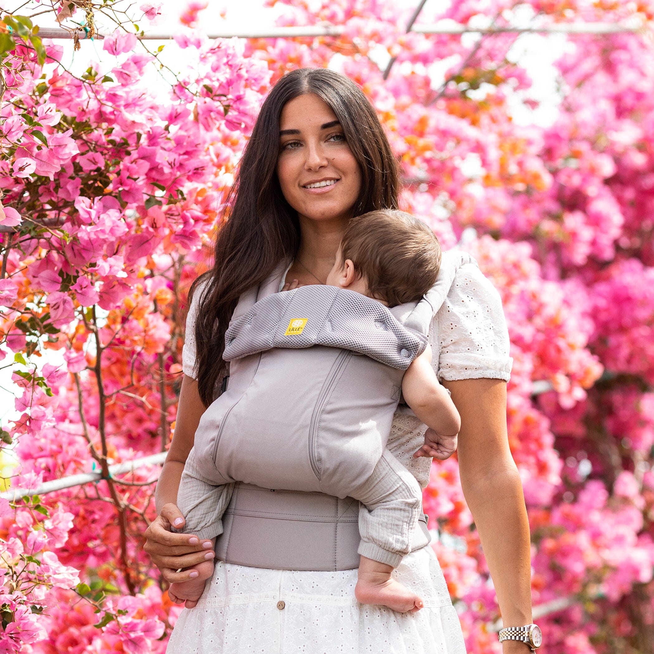 Mom wearing complete all seasons carrier in stone color with 5 month old infant in narrow ergonomic seat