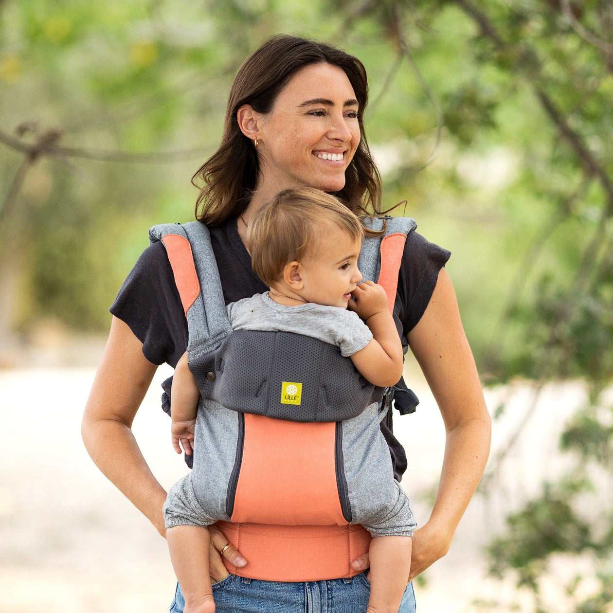mom wearing baby in lillebaby complete all seasons baby carrier in cool coral