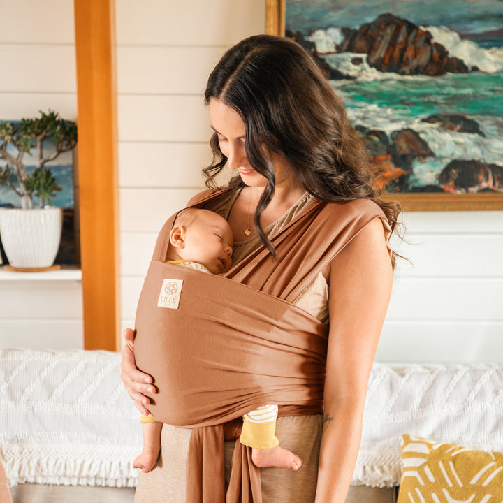 mom wearing baby in the dragonfly wrap in butterscotch