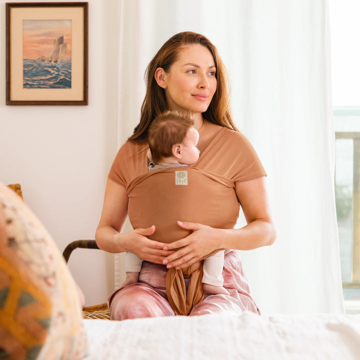 mom wearing baby in the dragonfly wrap in butterscotch