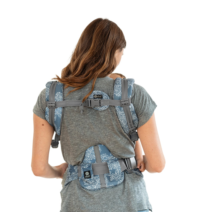 back image of mom wearing baby in lillebaby complete luxe baby carrier in starfall